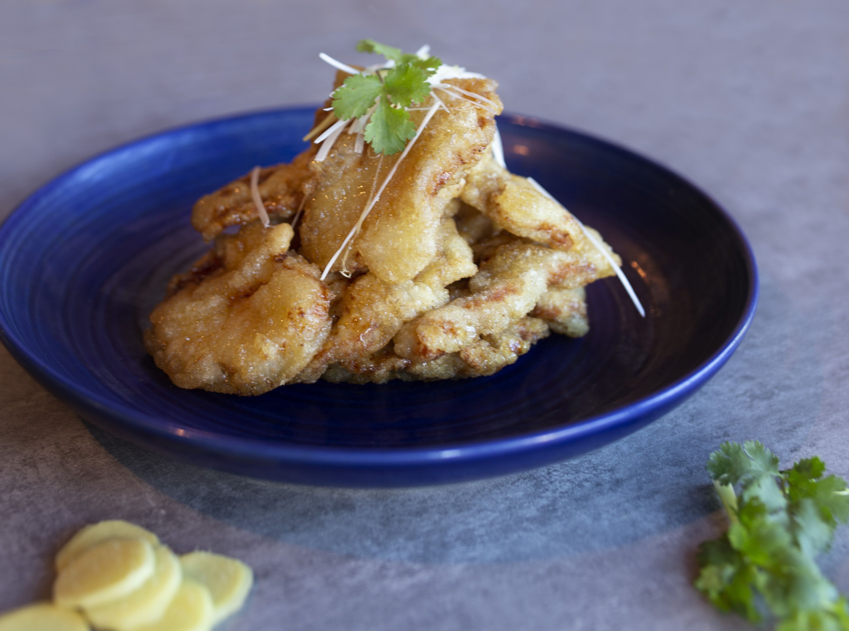 A blue plate with fried food garnished with cilantro.