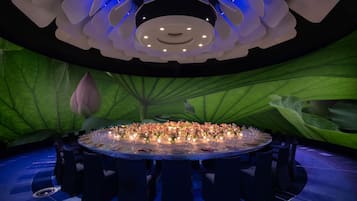 A round table set for a formal event, surrounded by dark chairs, with a floral arrangement and candles on the table.