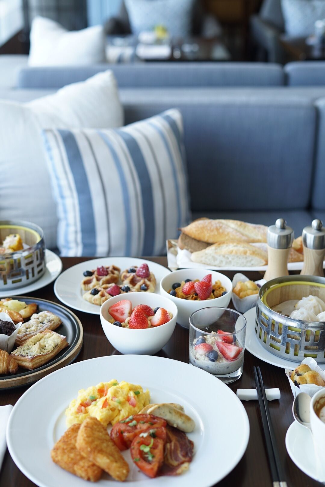 En morgenmadsbuffet med forskellige retter, herunder røræg, bagværk og frugt.