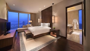 A modern hotel room with a large bed, a TV, a seating area, and a view of the cityscape. - Grand Hyatt Macau (Cotai)