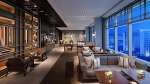 A modern interior with a sofa set, a dining area, and a large window offering a city view. - Grand Hyatt Macau (Cotai)