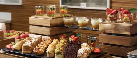 Variedad de pasteles y postres exhibidos sobre pedestales de madera.