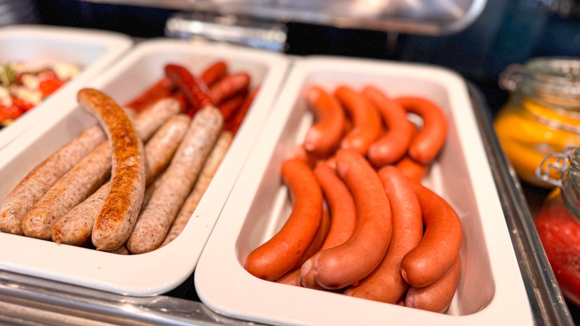 Un buffet proposant différents types de saucisses, présentées dans des plateaux.