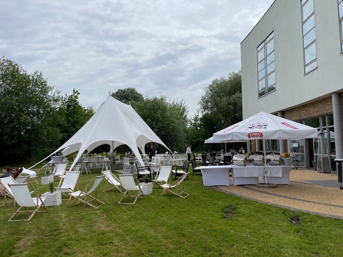 Un événement en plein air avec une tente blanche et des fauteuils confortables installés sur la pelouse.