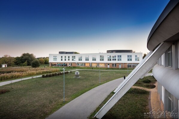 A modern building with a flat roof, large windows, and a paved walkway. - Hotel Victor Pruszków DeSilva (Pruszkow)