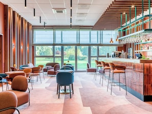 A modern bar area with a bar counter, seating, and a view of the outdoors.