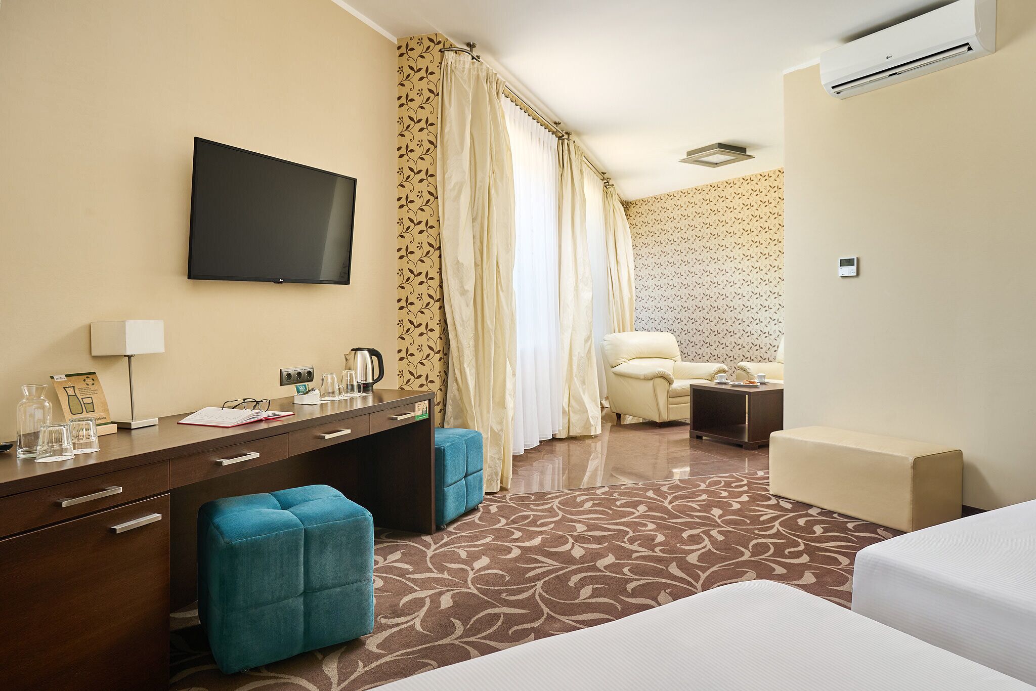 Een hotelkamer met een flatscreen televisie, een bureau met koffiezetapparaat, een sofa, een stoel en een bed.