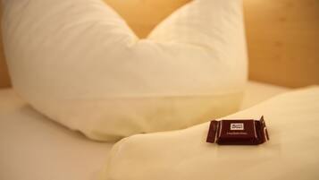 Una almohada y una tableta de chocolate Ritter Sport sabor amargo sobre una cama.