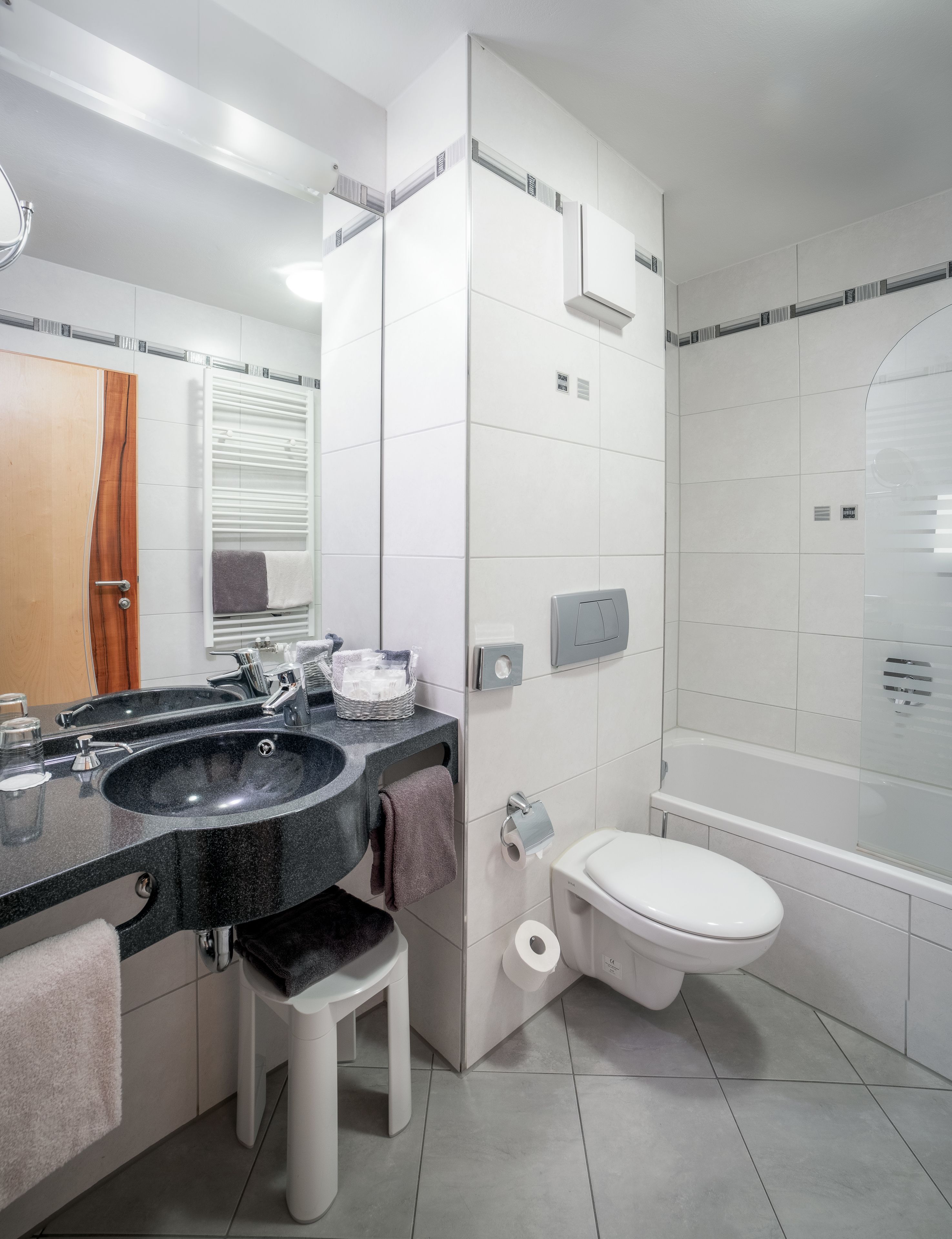 A modern bathroom with a black sink, a toilet, and a bathtub.