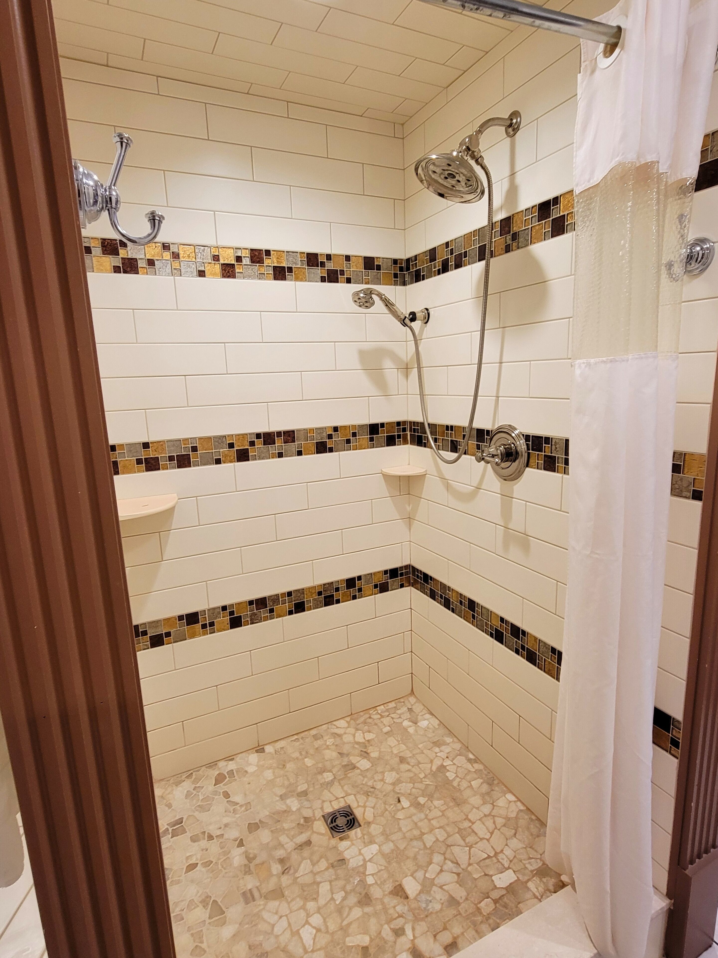 A shower area with a tiled floor, a showerhead, and a curtain.