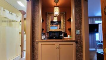 A hallway with a wooden cabinet, a mirror, and a chandelier.