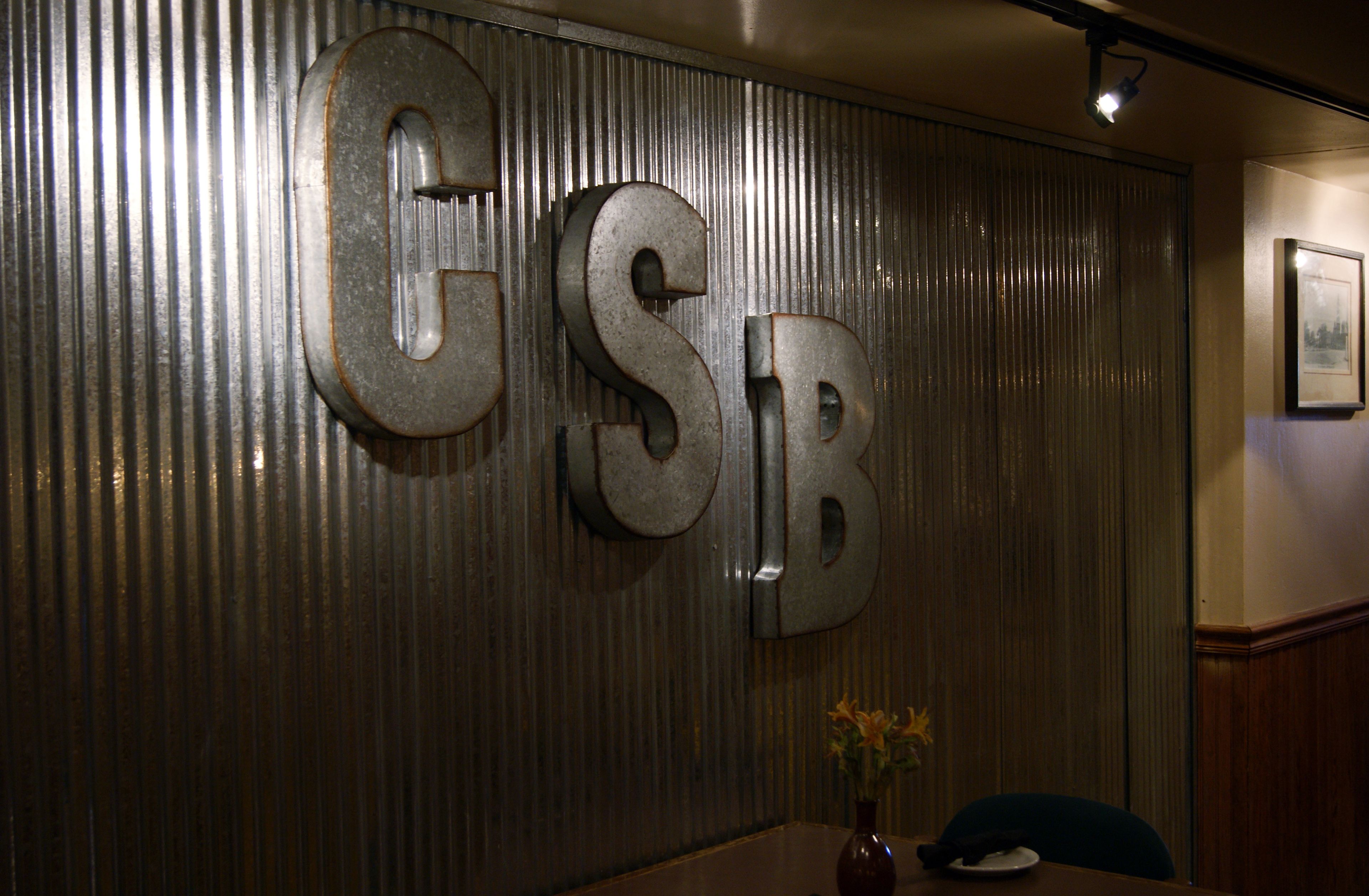 A wall with large metallic letters spelling "GSB".