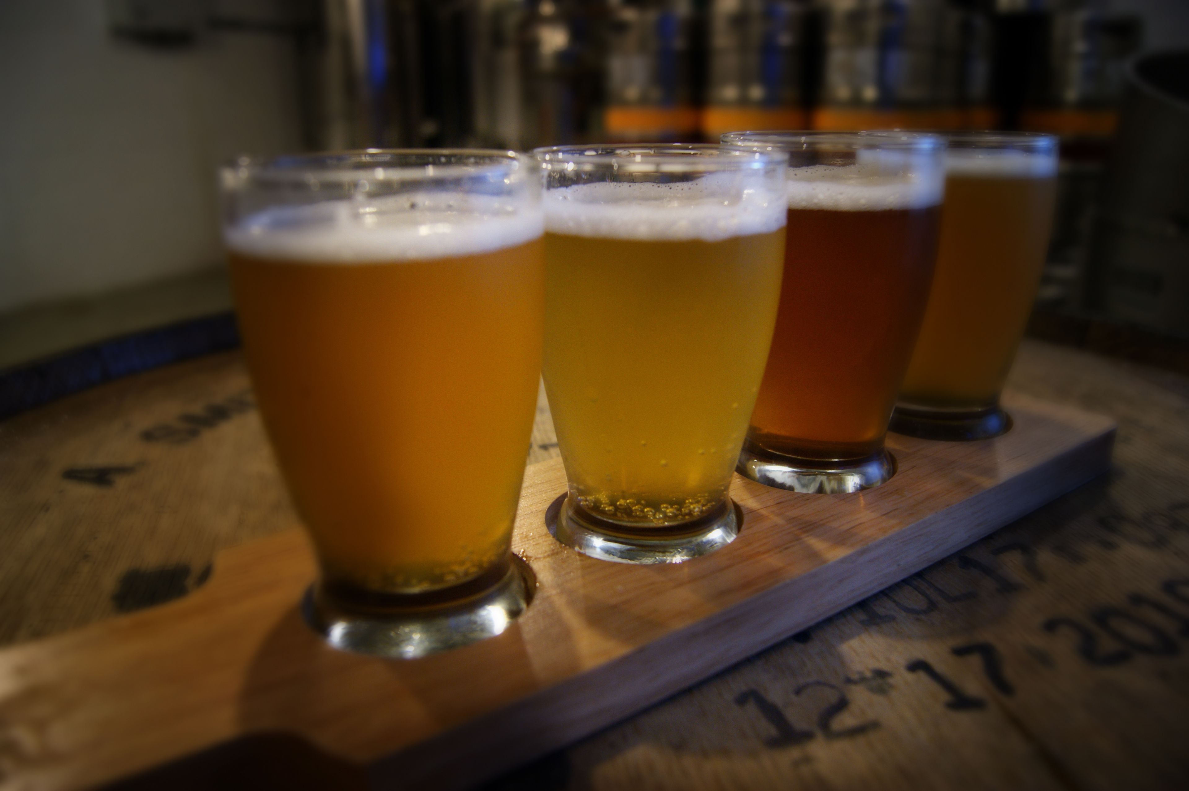 Quatre verres de bière sur un plateau en bois, avec une indication de la date.