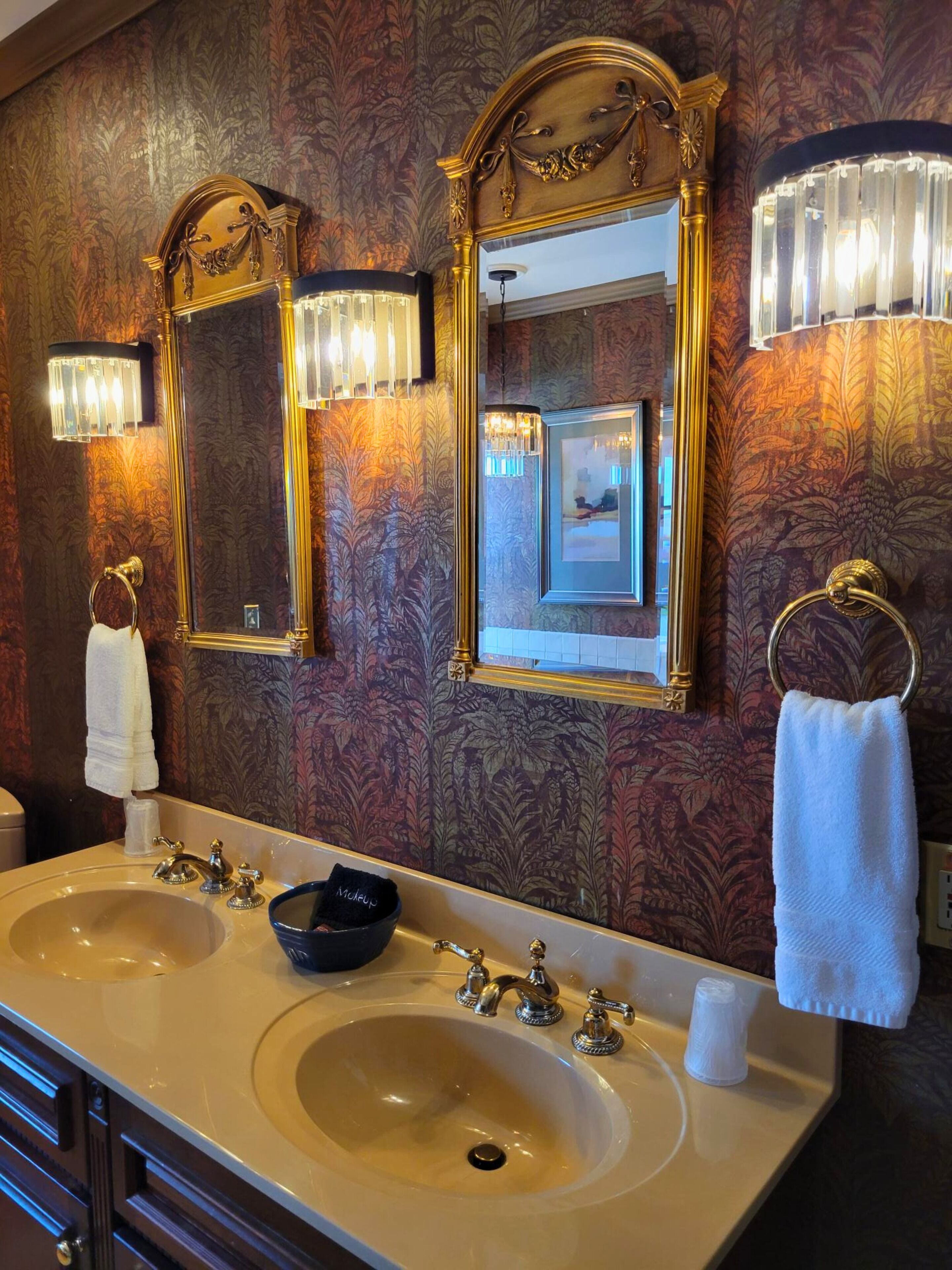 A bathroom with two sinks, a mirror, and wall sconces.