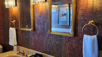 A bathroom with two sinks, a mirror, and wall sconces.