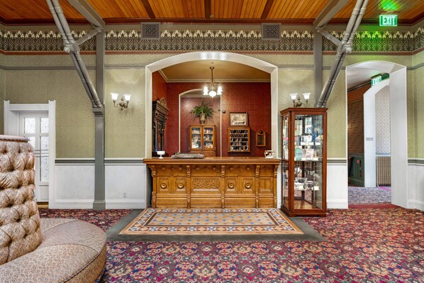 A lobby with a wooden reception desk, a patterned carpet, and a tufted leather bench.