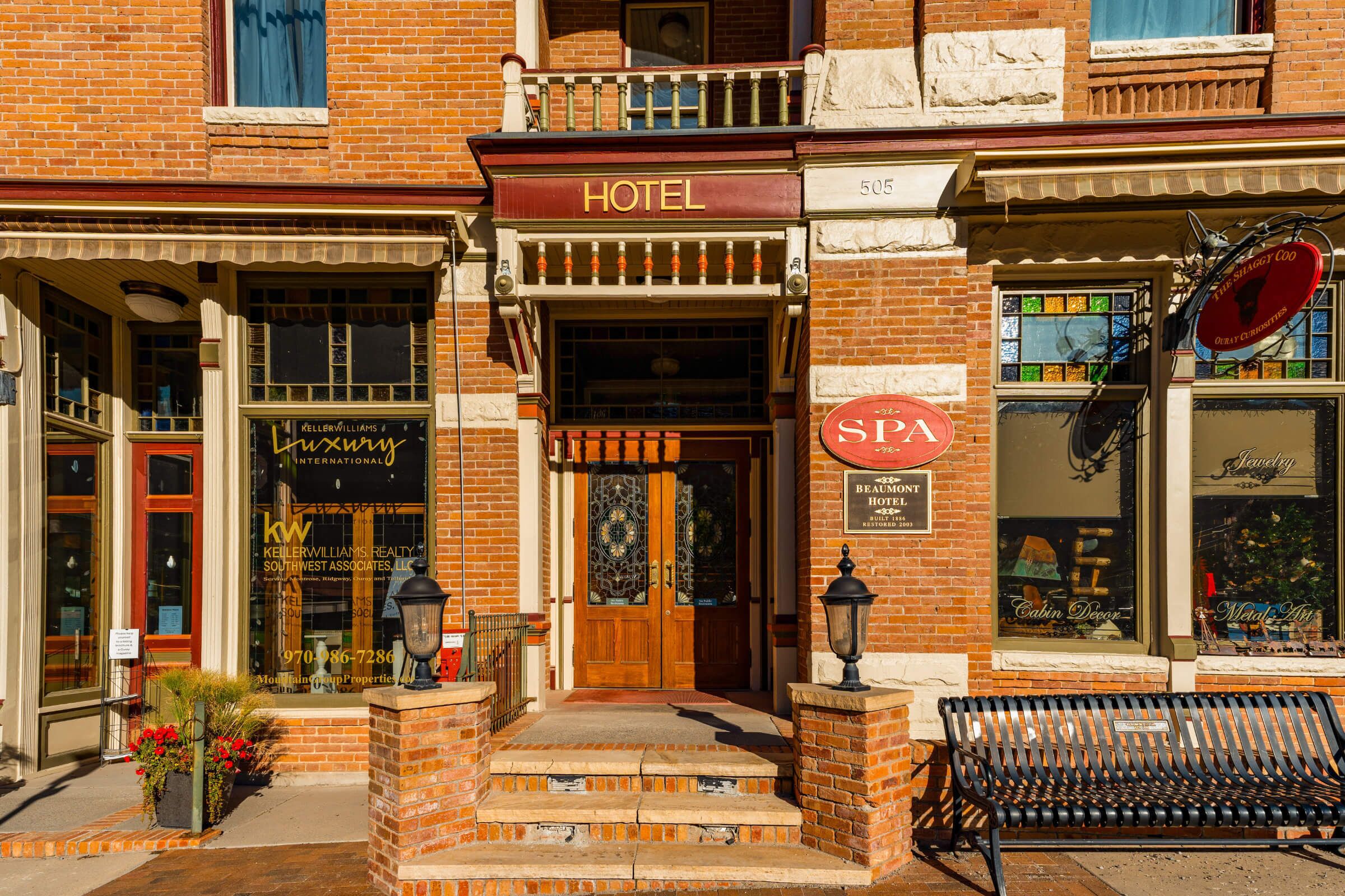 A hotel with a wooden front door, a sign for a spa, and a bench outside.