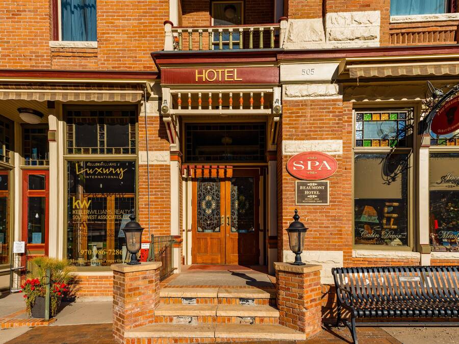 A hotel with a wooden front door, a sign for a spa, and a bench outside.