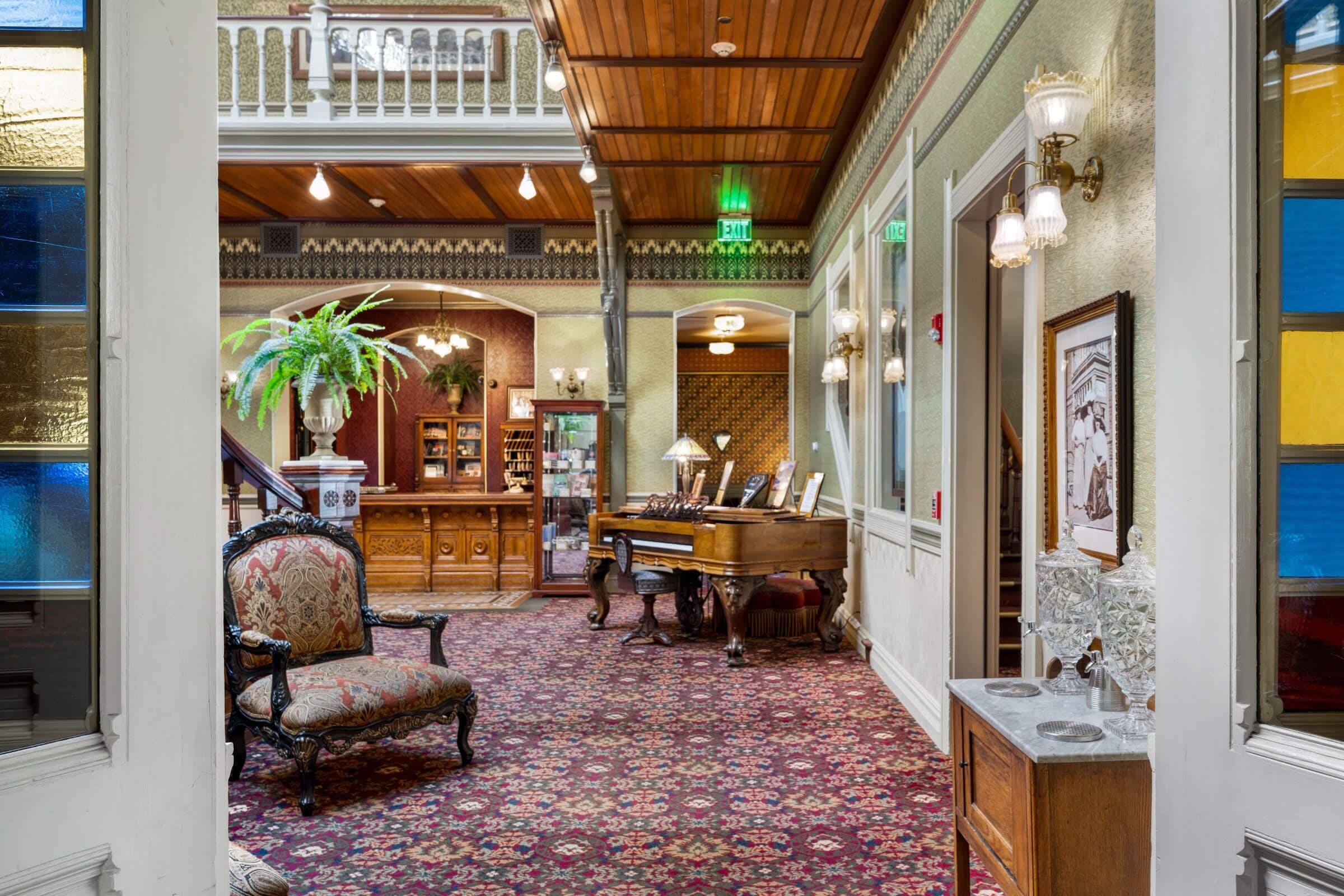 A grand lobby with a piano, a large armchair, and a bookshelf.