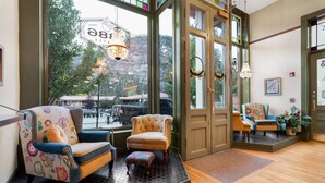 A cozy lobby with a large window, a comfortable seating area, and a door leading outside. - Beaumont Hotel & Spa - Adults Only (Ouray)