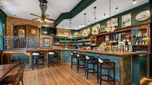 A bar area with wooden flooring, bar stools, a counter with bottles, and a staircase. - Beaumont Hotel & Spa - Adults Only (Ouray)