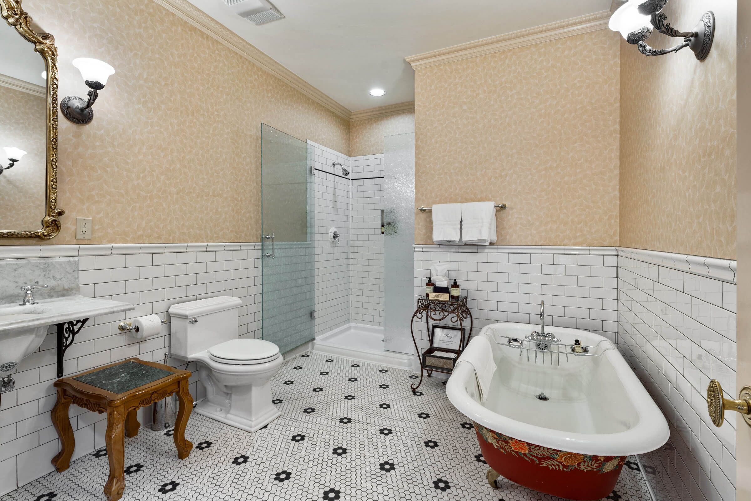 A bathroom with a white toilet, a sink, a shower, and a red bathtub.