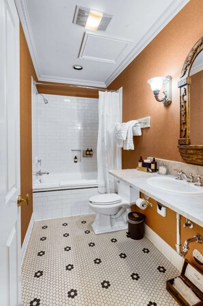 A bathroom with a white toilet, a bathtub, and a shower. There is a vanity with a mirror and a sink. The floor has a patterned tile design. - Beaumont Hotel & Spa - Adults Only (Ouray)