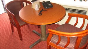 A small round wooden table with a telephone and a plastic container on it. There are two wooden chairs with woven seats. - Royal Inn Motel Long Beach (Long Beach)
