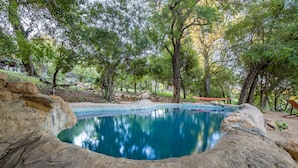 A natural pool surrounded by large rocks and trees. - Umlani Bushcamp - Lodge (Bushbuckridge)