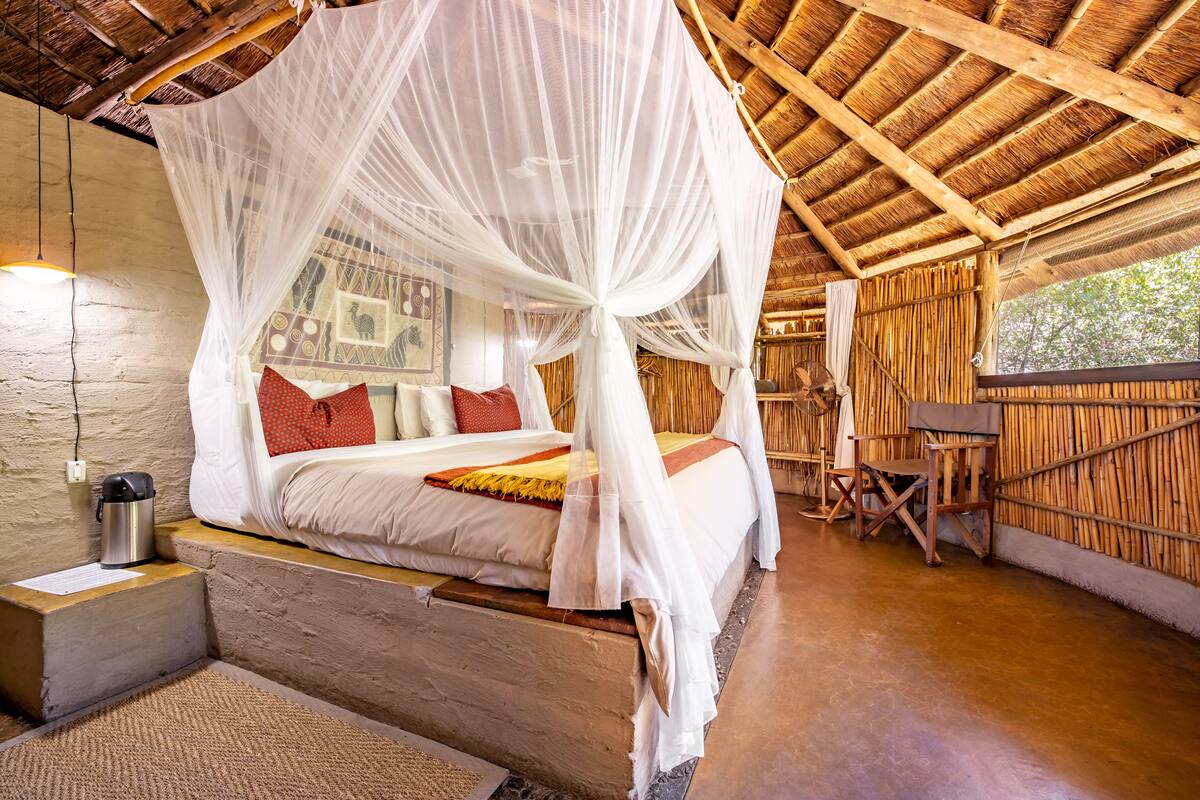 Ein Zimmer mit einem Bett unter einem Baldachin, einem Holztisch und einem Stuhl.