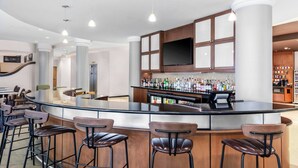 Zona de bar moderna con una barra curva, taburetes y una variedad de botellas de licor.