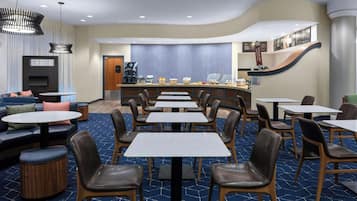 A modern hotel lobby with a bar area, seating arrangements, and a television.