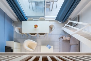 Une pièce moderne comprenant une table à manger, des chaises, un canapé, un téléviseur et un escalier.