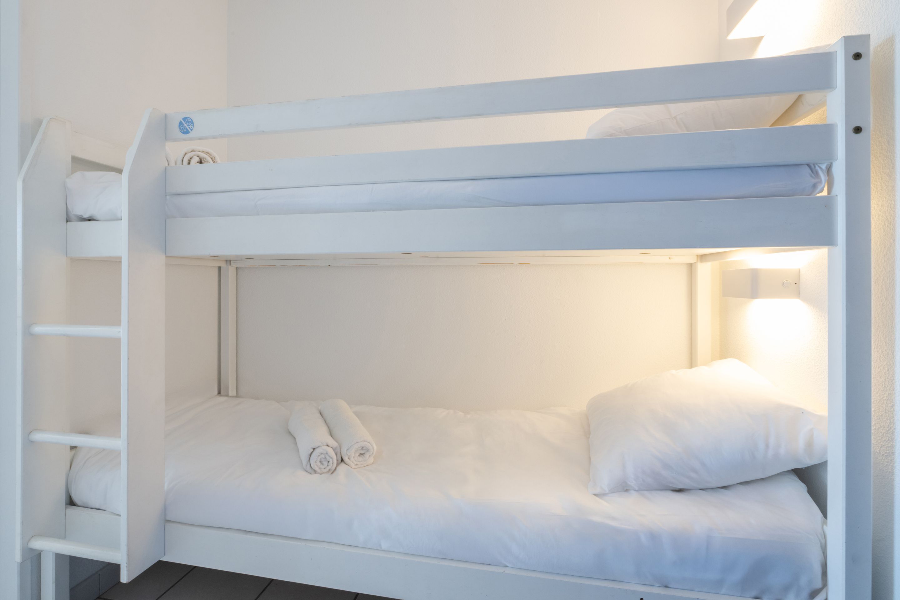 A bunk bed with white bedding and a headboard.