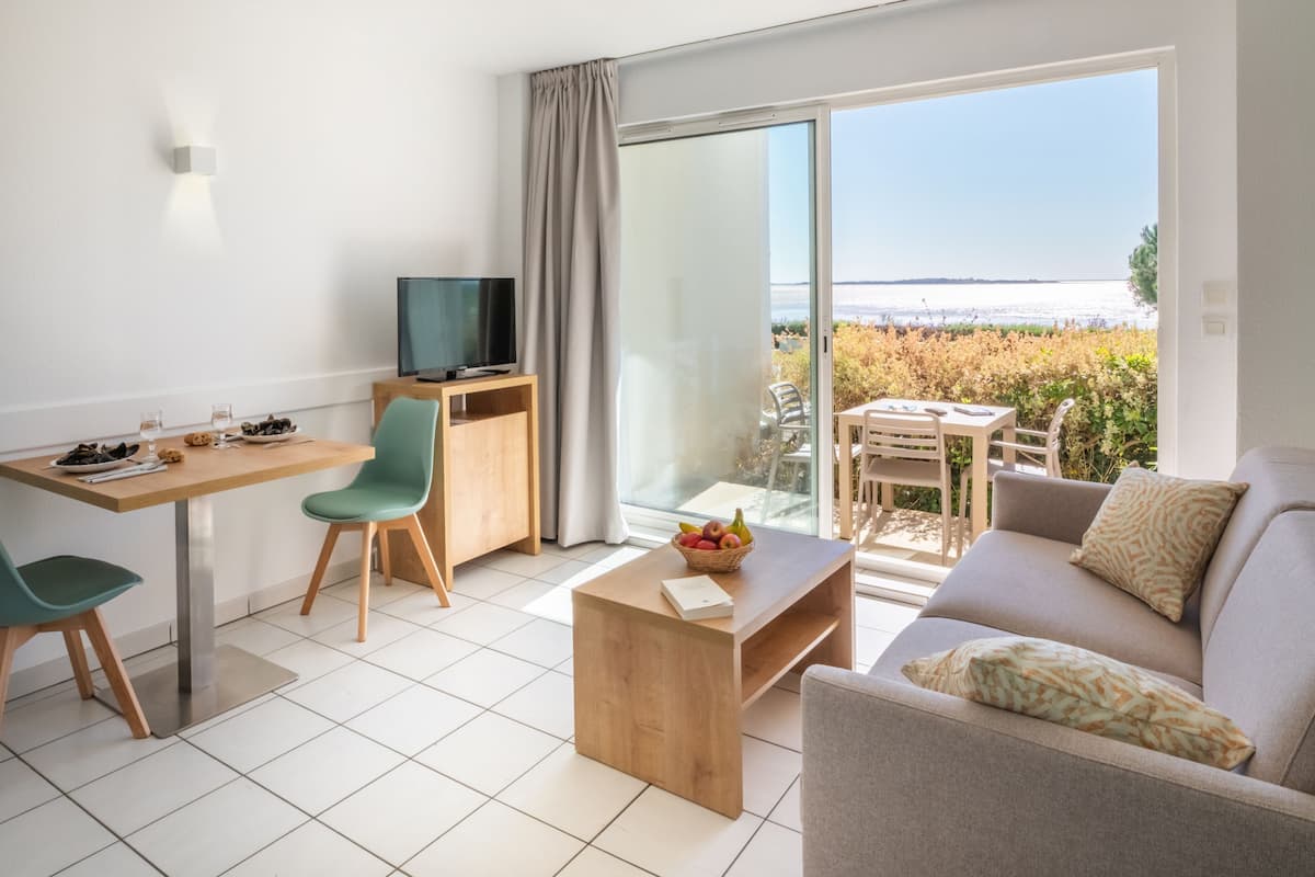 Un salon moderne comprenant un canapé, une table basse, un téléviseur et un coin repas avec des chaises et une table.