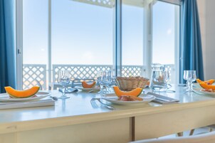 Une table à manger dressée avec des assiettes, des couverts, des verres et un panier de pain.