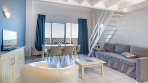 A modern living room with a dining area, a sofa, a TV, and a staircase. - Résidence Odalys Les Terrasses de Fort Boyard (Fouras)