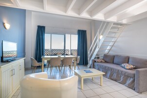 Un salon moderne comprenant un coin repas, un canapé, un téléviseur et un escalier.