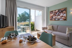 Un coin repas avec une table dressée pour deux personnes, un canapé et un téléviseur.