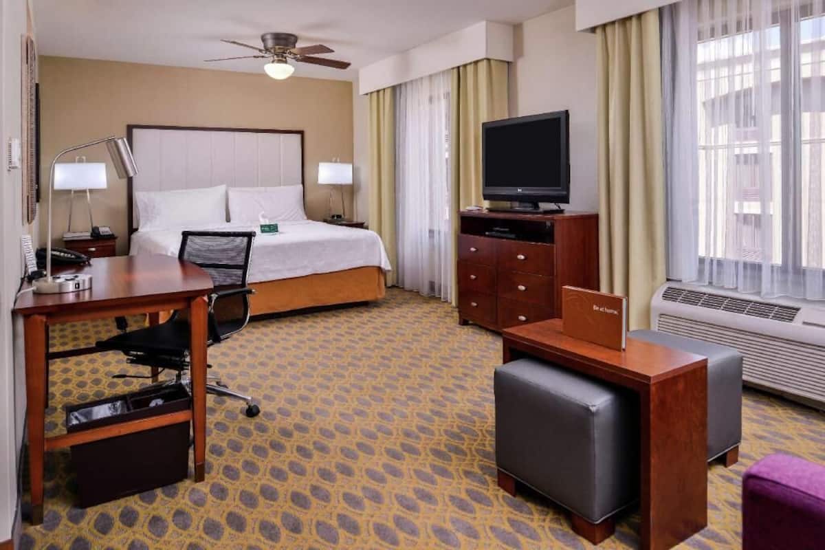 Une chambre d’hôtel équipée d’un lit, d’un bureau, d’une chaise, d’une télévision et d’un appareil de climatisation.