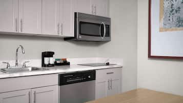 A modern kitchen with white cabinetry, a stainless steel microwave, a coffee maker, and a dishwasher.