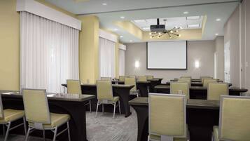 Un salón de conferencias con varias mesas y sillas, una pantalla de proyector y una lámpara en el techo.