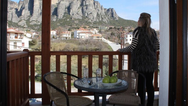 A balcony with a view of rocky mountains and a town. - Famissi Hotel (Kalabaka)