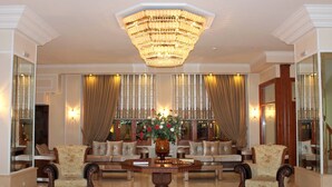 A grand lobby with a large chandelier, plush seating, and a decorative vase with flowers. - Famissi Hotel (Kalabaka)