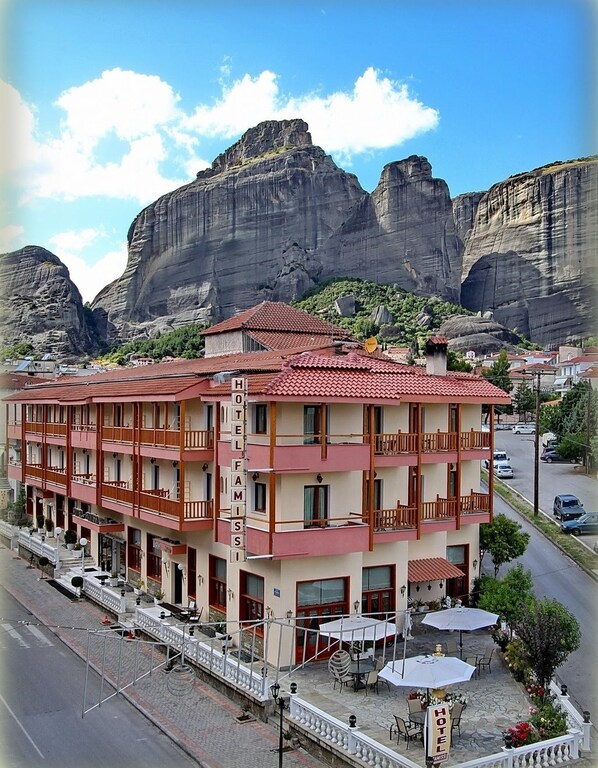A hotel with multiple floors, balconies, and outdoor seating areas. - Famissi Hotel (Kalabaka)