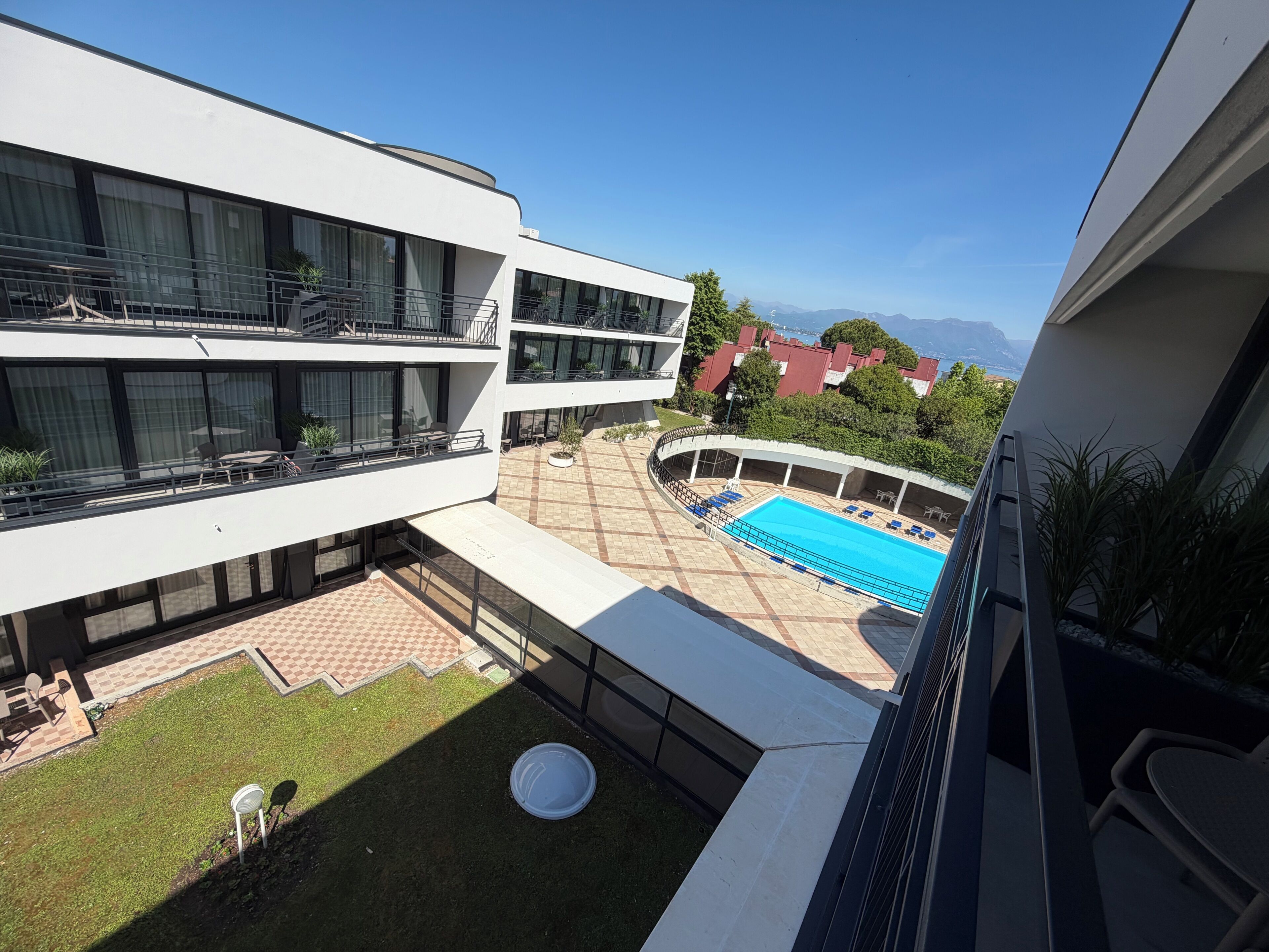 A modern building with a rooftop pool, outdoor seating, and a view of distant mountains.