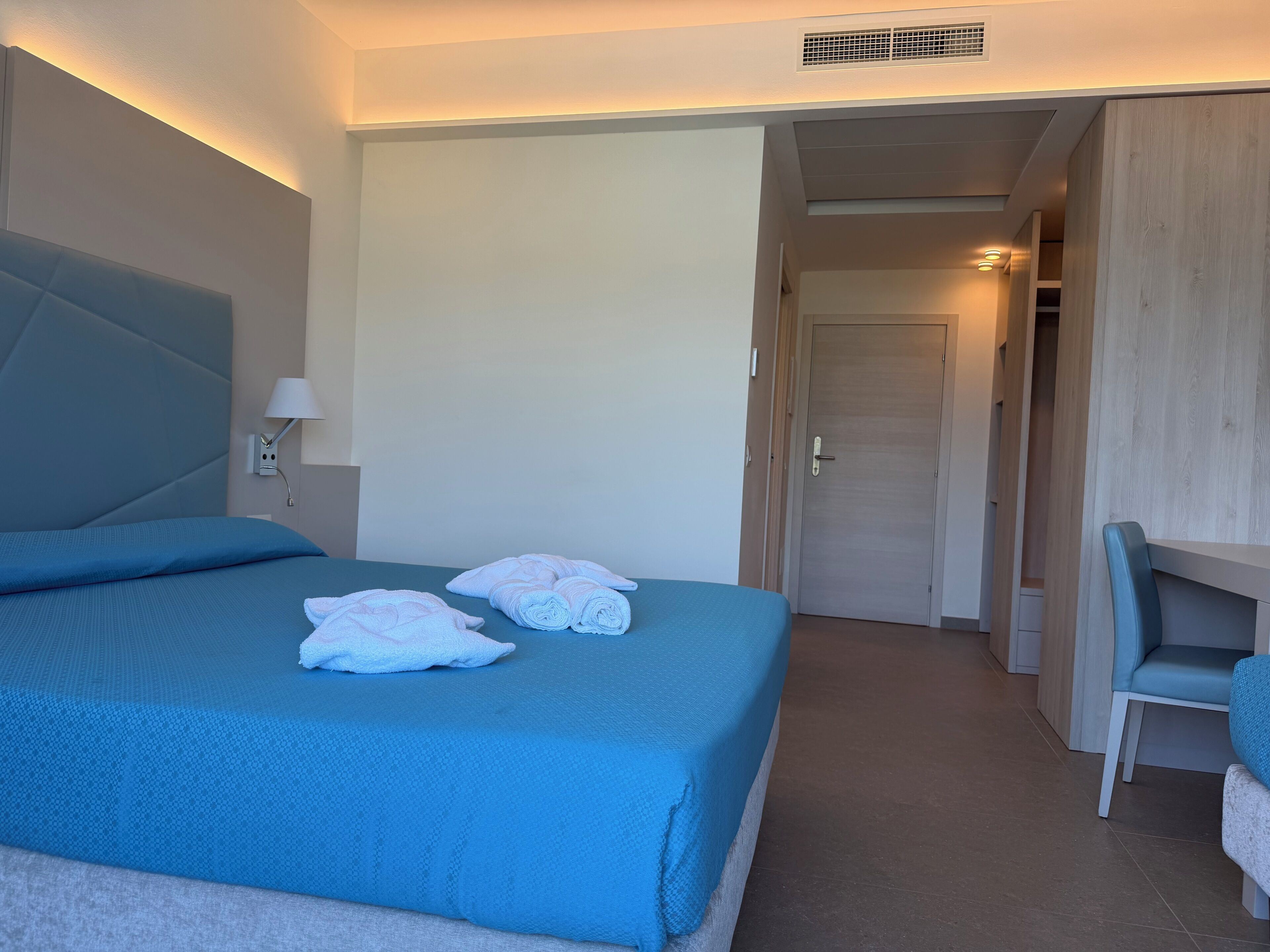 Een hotelkamer met een bed, een bureau en een kledingkast.