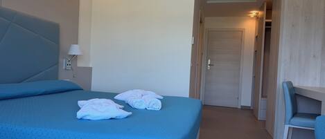 Een hotelkamer met een bed, een bureau en een kledingkast.