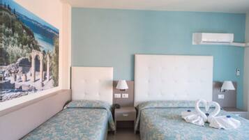 Habitación de hotel con dos camas, un ventanal grande con vistas a ruinas y un equipo de aire acondicionado en la pared.