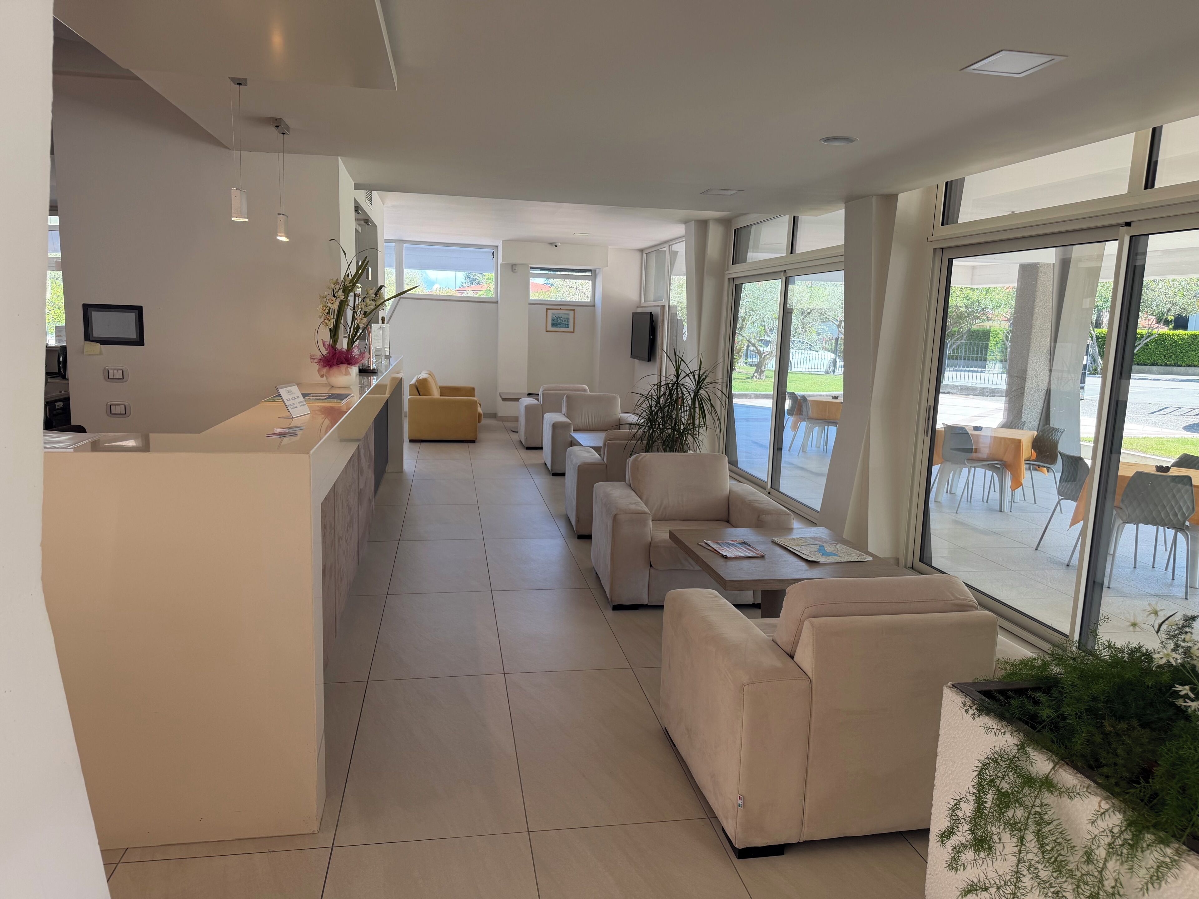 A modern hotel lobby with a reception desk, seating area, and large windows offering views of the outdoors.